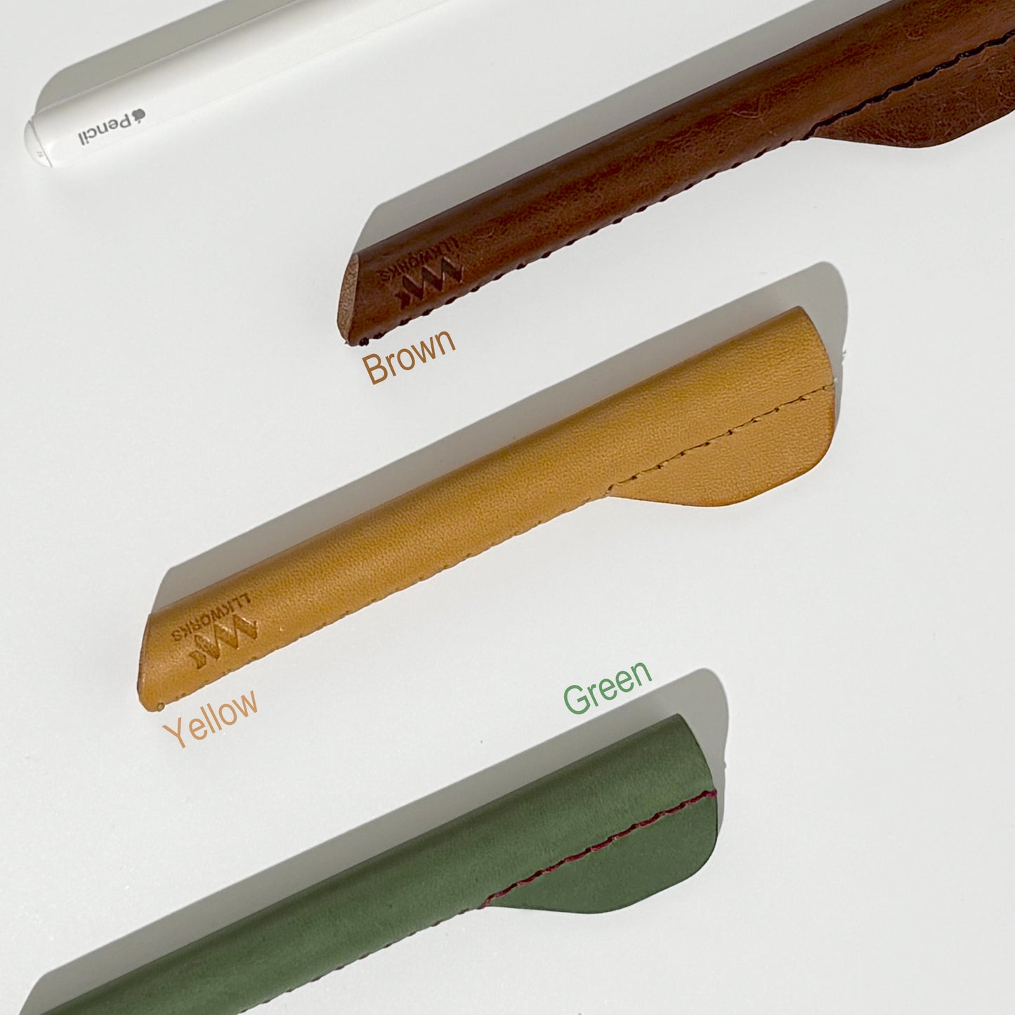 Collection of artisan-crafted leather ergonomic grips for Apple Pencil, available in brown, yellow, and green, designed for enhanced comfort and control.