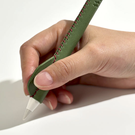 Close-up of a hand using an Apple Pencil with a comfortable, green handmade leather ergonomic grip, enhancing writing and drawing experience.