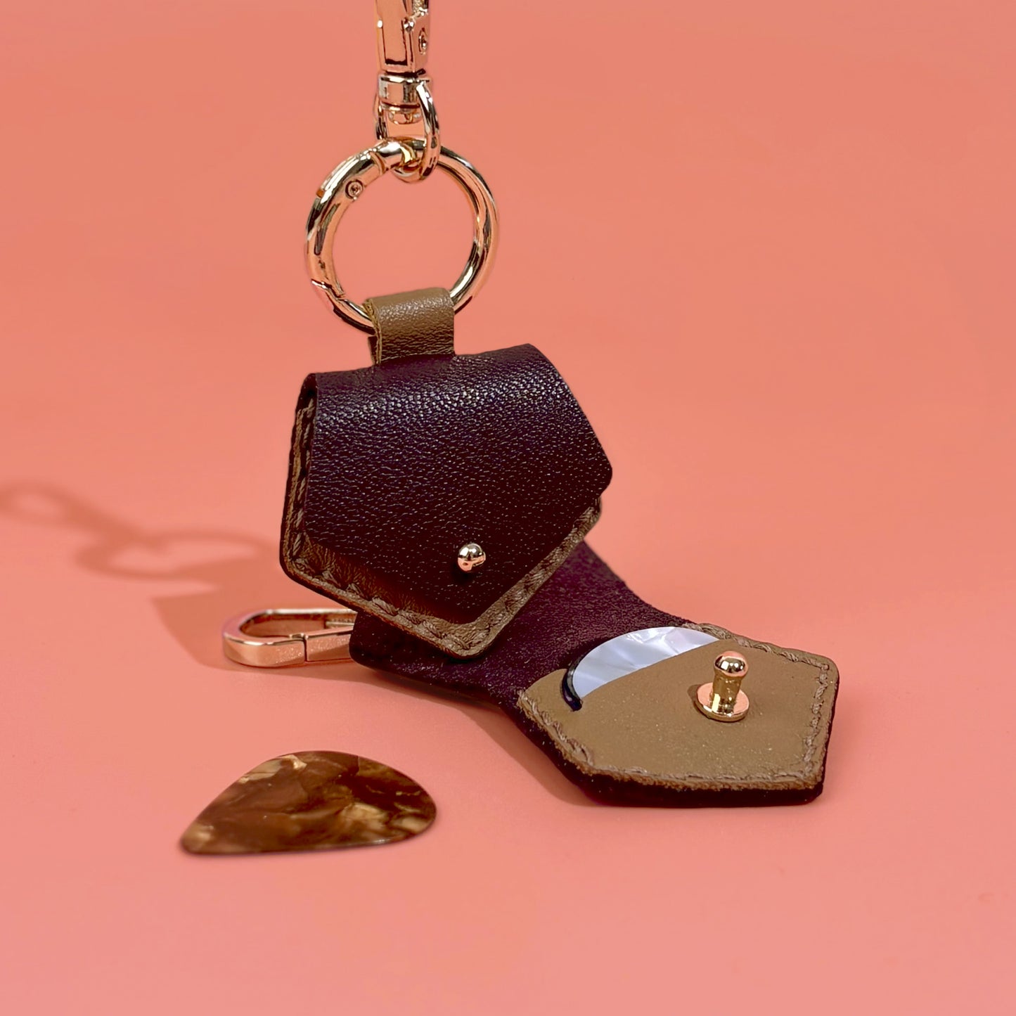 Durable dark brown leather guitar pick organizer keychain, providing a compact and fashionable way to store and carry your favorite guitar picks.
