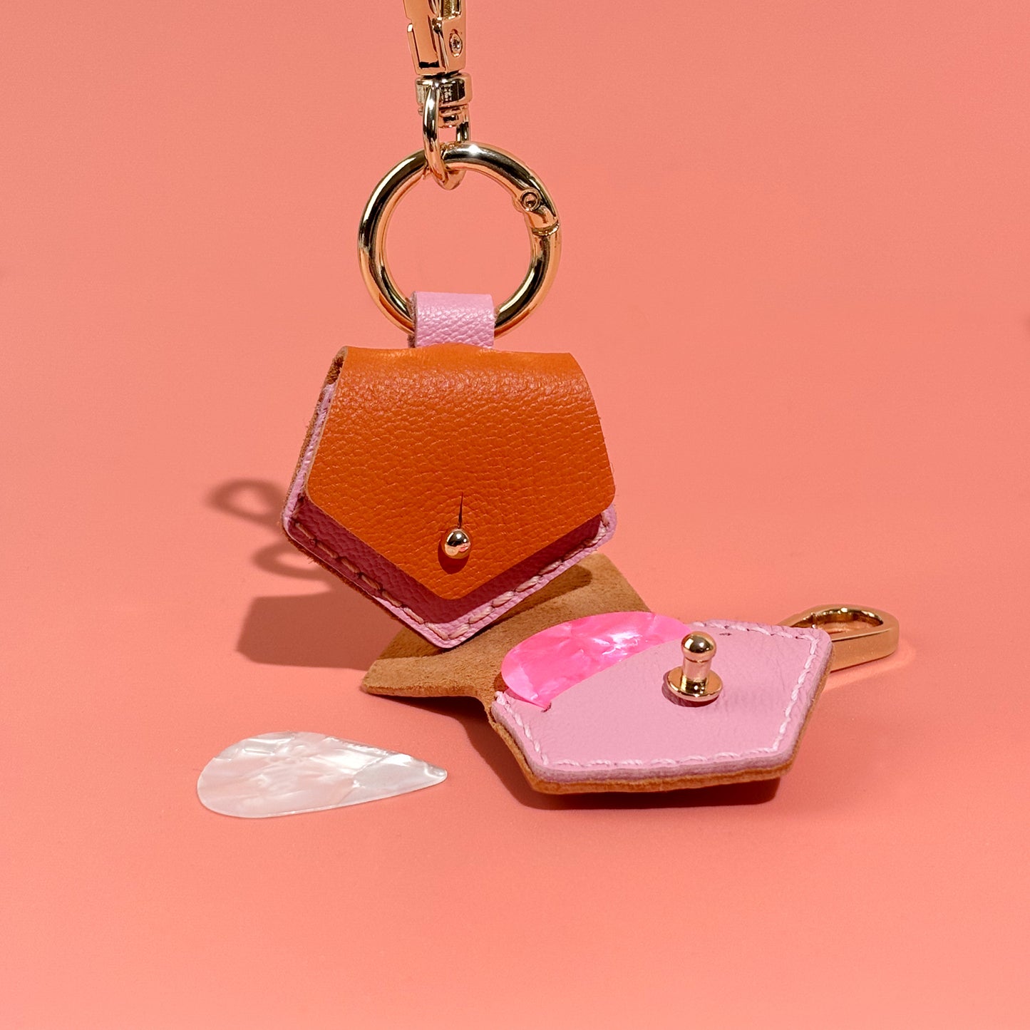 Vibrant orange handmade leather guitar pick case keychain, designed for musicians who need a convenient and elegant solution for pick safekeeping.