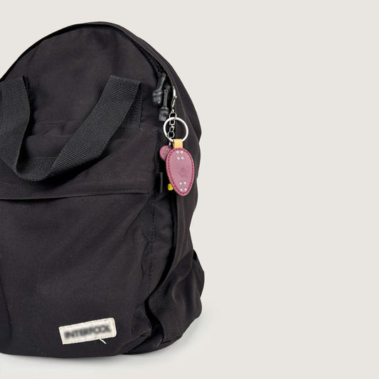 Black backpack styled with a Purple Mini Skateboard bag charm/bag pendant.