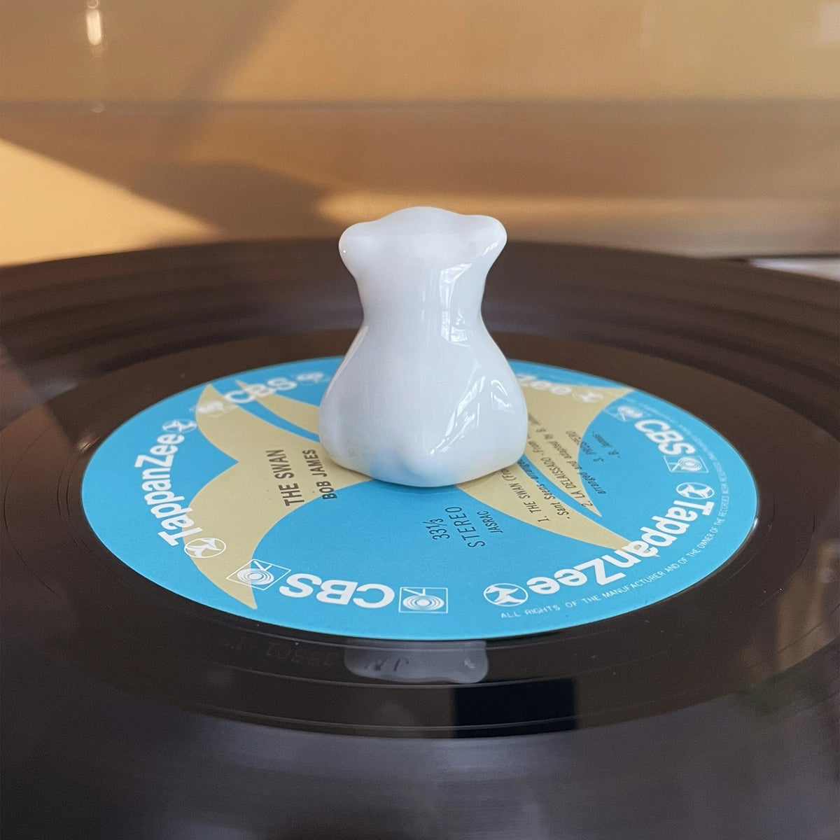 Back view of smooth white ceramic bear ornament placed on a vintage record player