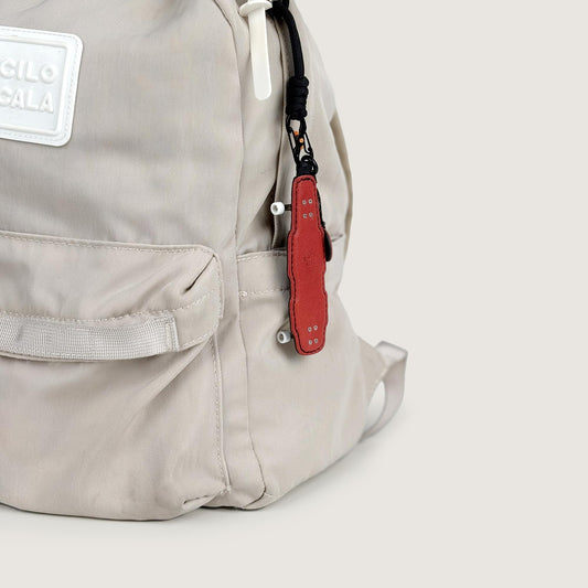 Longboard-shaped veg-tan leather keychain used as a stylish bag accessory, featuring NFC NTAG213 functionality and handcrafted skateboard-inspired details.