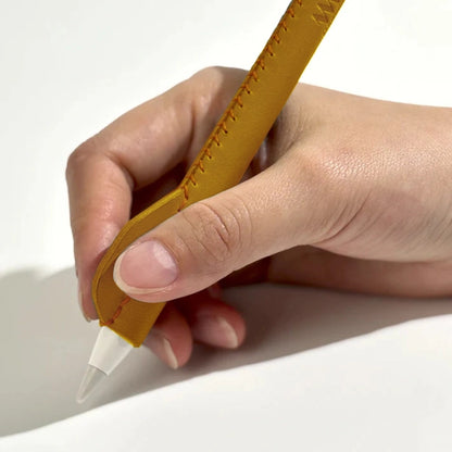 Hand holding Apple Pencil with ergonomic yellow leather sleeve grip while writing