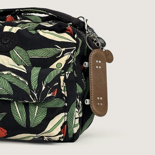 Leather double kick skateboard bag charm attached to a backpack as a daily accessory.