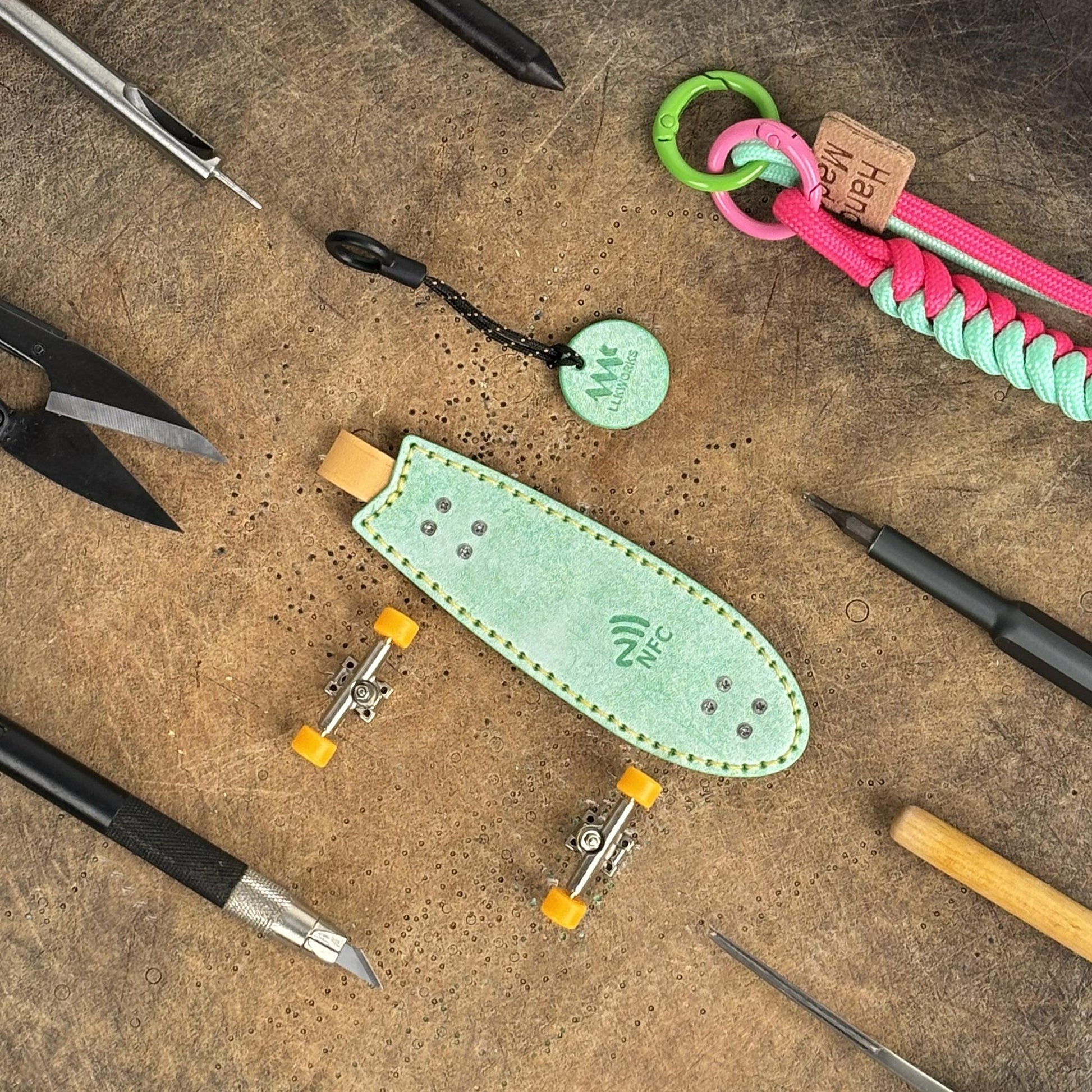 Handcrafted fingerboard keychain displayed with leatherworking tools, artisan quality.