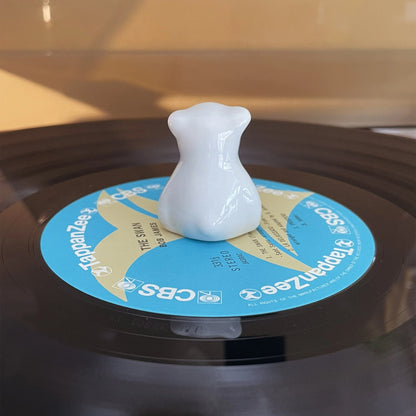 Back view of smooth white ceramic bear ornament placed on a vintage record player