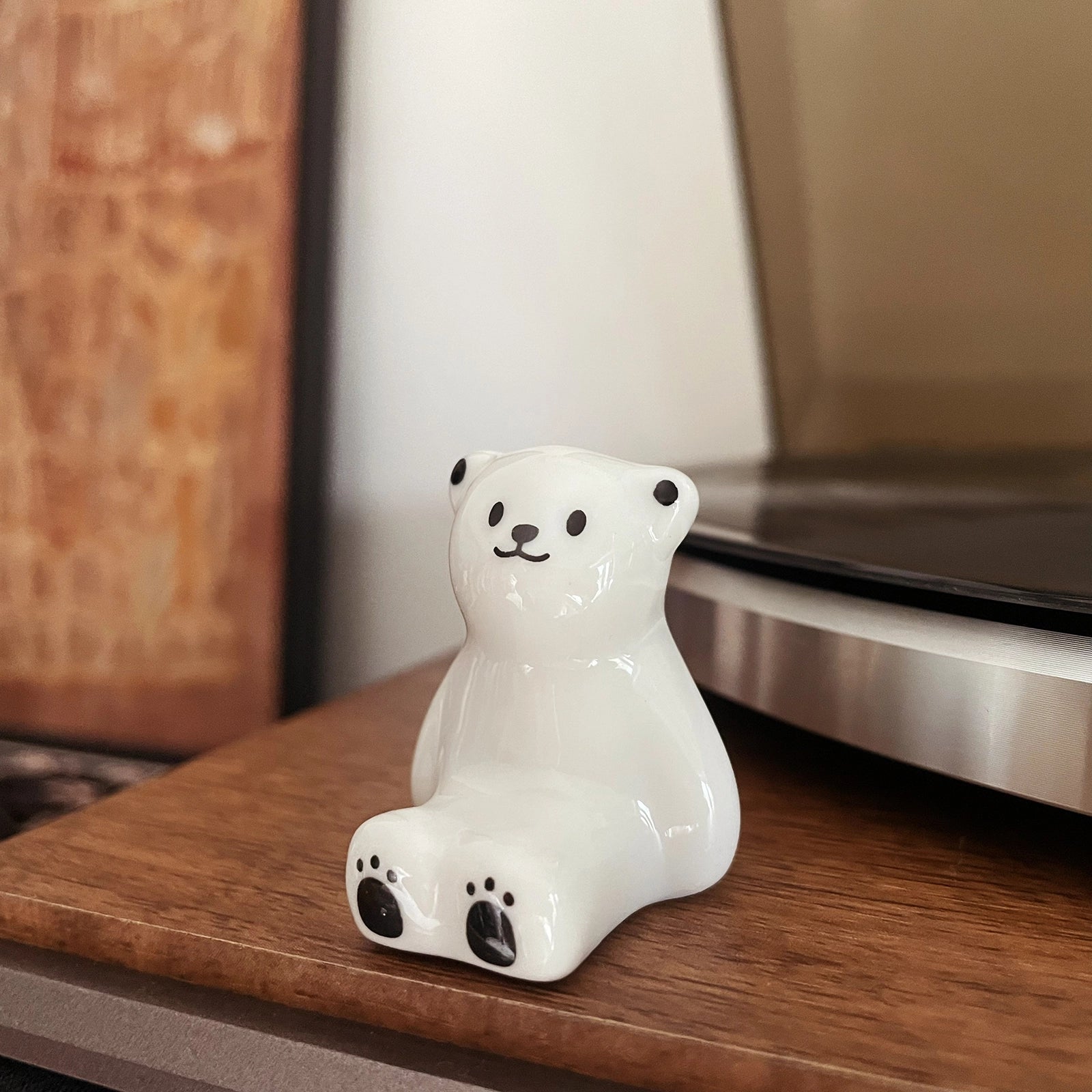 Handmade ceramic polar bear figurine display next to record player on wooden desk