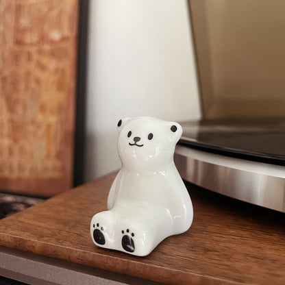 Handmade ceramic polar bear figurine display next to record player on wooden desk