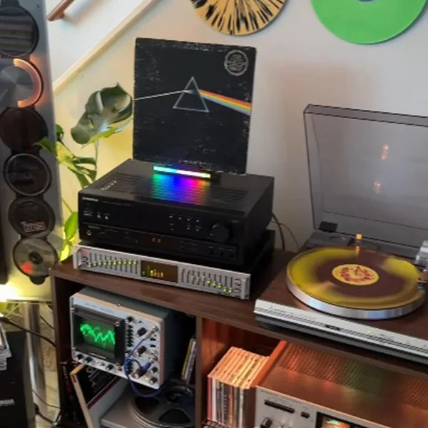 Pink Floyd The Dark Side of the Moon vinyl record album displayed on a sound-reactive RGB LED now playing stand, next to a vintage turntable and audiophile stereo setup by @cam.in.the.wild.